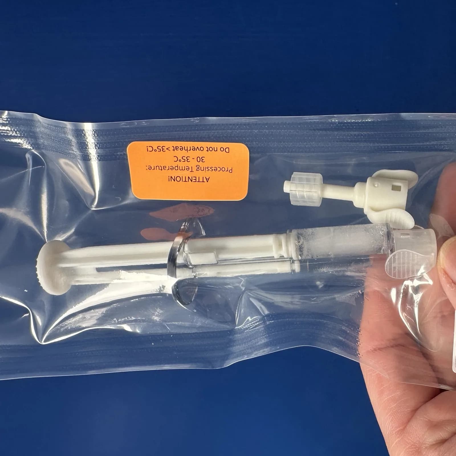 A ChondroFiller liquid syringe and its mixing adapter sealed in the sterile blister, held in a hand