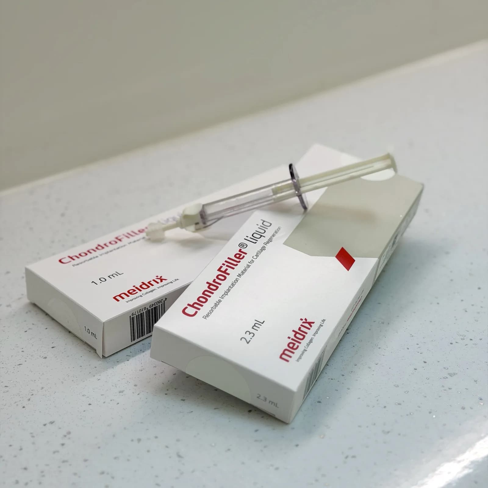ChondroFiller liquid 1.0 ml and 2.3 ml packs with a pre-filled dual-chamber syringe resting on them